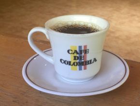 a steaming cup of hot coffee in a cup that says "cafe de colombia"